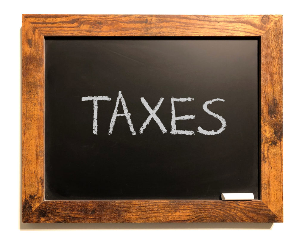 Chalk board with the word TAXES drawn on it highlighting the post about tax loopholes for Irish investors